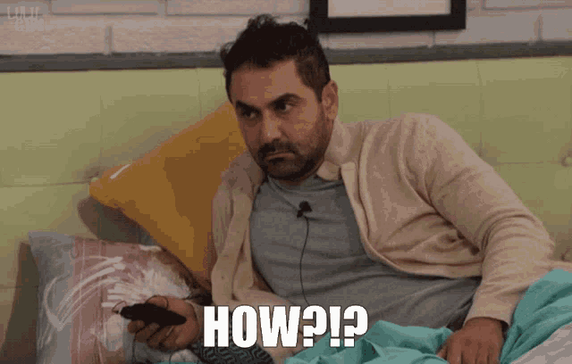 a man is laying in bed holding a remote control and the word how is on the bottom