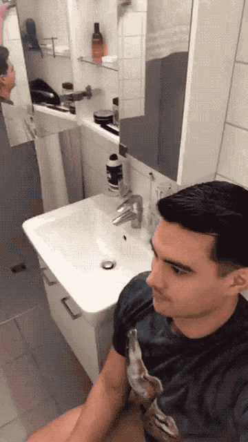 a man is sitting in front of a bathroom sink