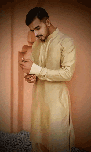 a man in a tan shirt is adjusting his cuffs