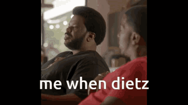 a man with a beard is sitting next to another man and says me when dietz