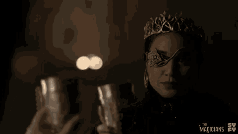 a woman wearing a tiara and a mask is holding a candle and glasses .