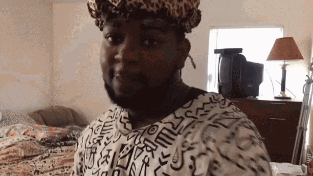 a man wearing a leopard print hat and a shirt with a pattern that says ' s ' on it