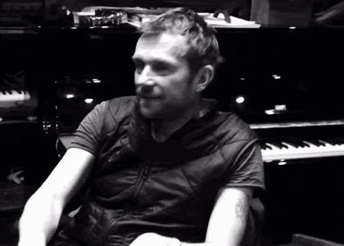 a man with a tattoo on his arm is sitting in front of a keyboard