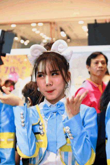 a girl wearing bunny ears and a bow tie stands in front of a crowd