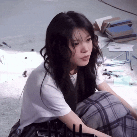 a girl is sitting on the floor in front of a stack of books