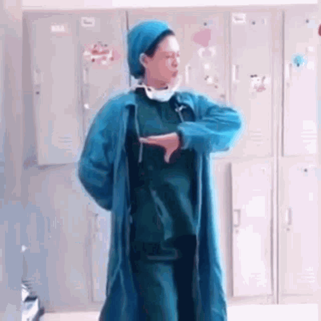 a female surgeon is dancing in a locker room in front of lockers .