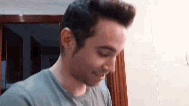 a man in a blue shirt is looking down and smiling