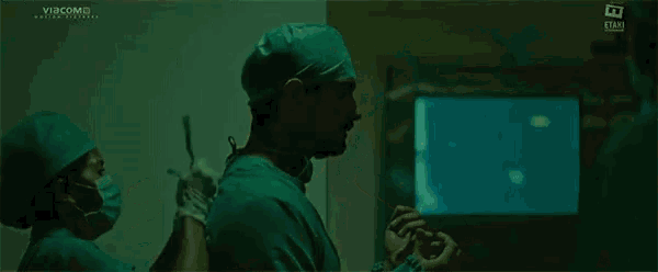 a surgeon wearing a mask is being helped by another surgeon