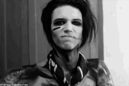 a black and white photo of a man with makeup on his face and a piercing in his lip .
