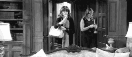 a black and white photo of two women standing in a living room .