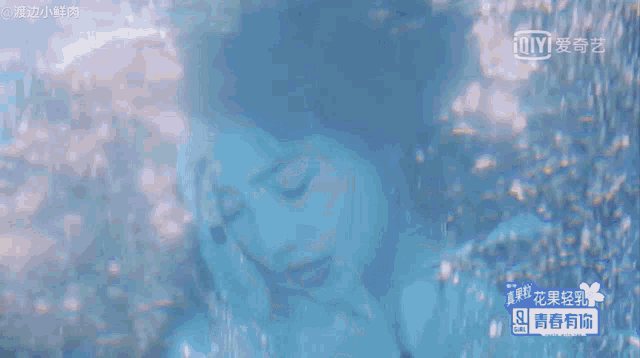 a woman in a blue dress is swimming in the water with an ioiyi logo behind her