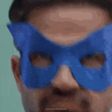 a man wearing a blue superhero mask is making a funny face .