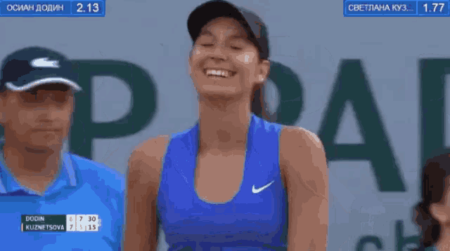 a woman wearing a blue nike tank top smiles while standing in front of a sign that says pa