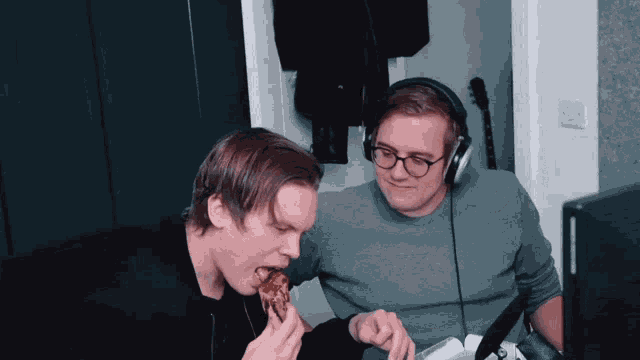 a man wearing headphones and glasses is eating a piece of pizza
