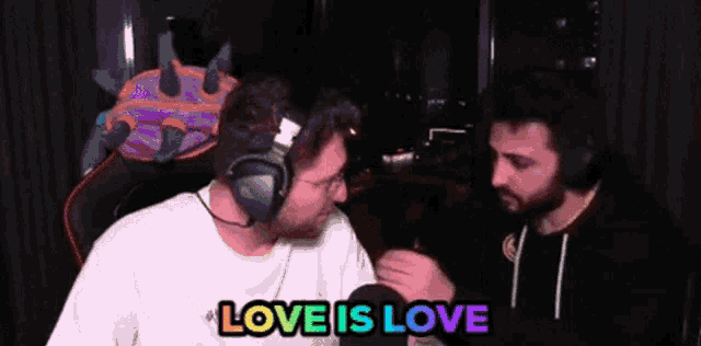two men wearing headphones are talking to each other and the words love is love are above them .