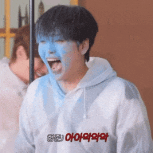 a person with blue paint on their face is wearing a white hoodie with chinese writing on it