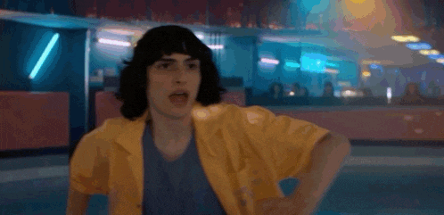 a man with curly hair is standing on a roller rink .