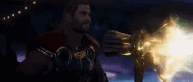 thor is holding a hammer that is glowing in the dark and a light is coming out of it .