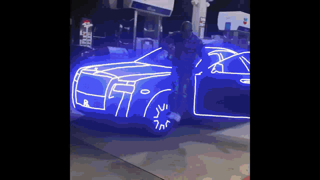 a man is standing in front of a blue car that is lit up