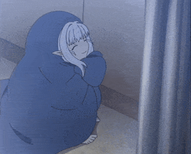 a person in a blue blanket sitting in a corner