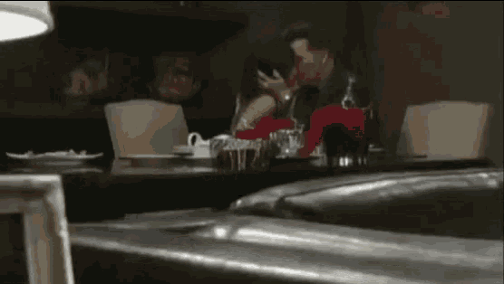 a man and woman are kissing at a table in a restaurant .