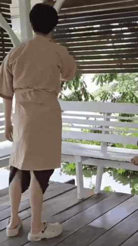 a person wearing a robe and crocs is standing on a porch