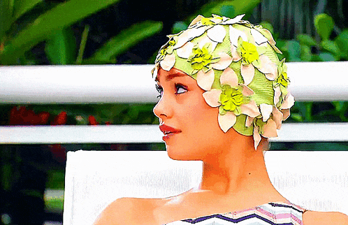 a woman wearing a floral swim cap sits on a chair
