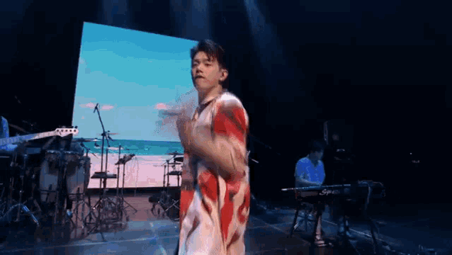 a man is dancing on a stage in front of a large screen while a man plays a keyboard .
