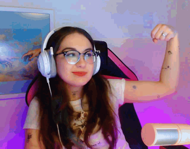 a woman wearing headphones flexes her arm in front of a painting that says " the creation of adam "