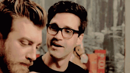 two men wearing glasses are looking at each other