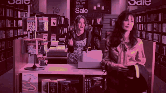two women in a bookstore with a sign that says sale on it