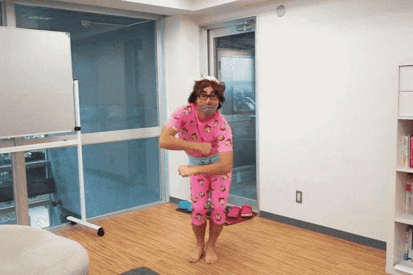a man in pink pajamas is dancing in a room with a window
