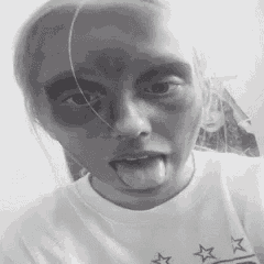 a woman wearing a white shirt with stars on it is sticking her tongue out