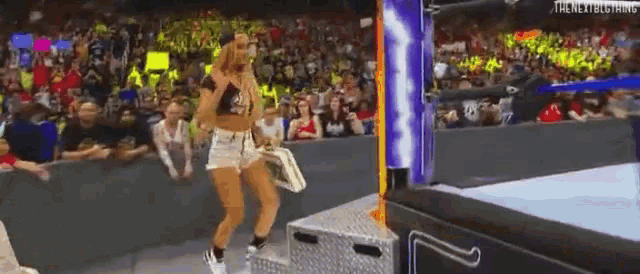a woman is walking out of a wrestling ring while holding a purse .