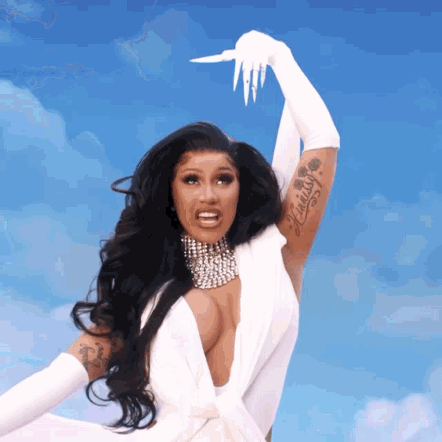 cardi b is wearing a white dress and white gloves and has a tattoo on her arm that says mistress