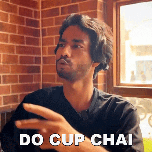a man with a beard says do cup chai in front of a window
