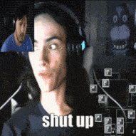 a man wearing headphones says shut up in front of a man wearing a blue shirt