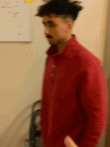 a man in a red jacket is standing in a room .