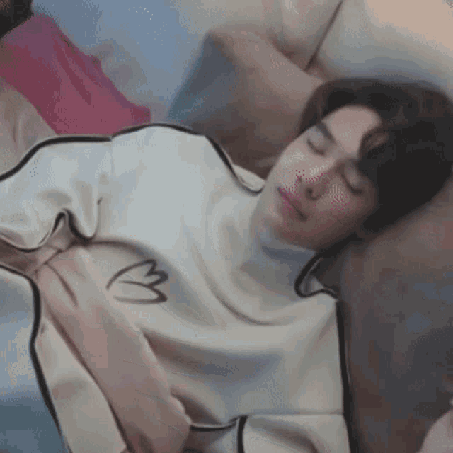 a man is sleeping on a couch with his eyes closed and his shirt has the letter b on it .