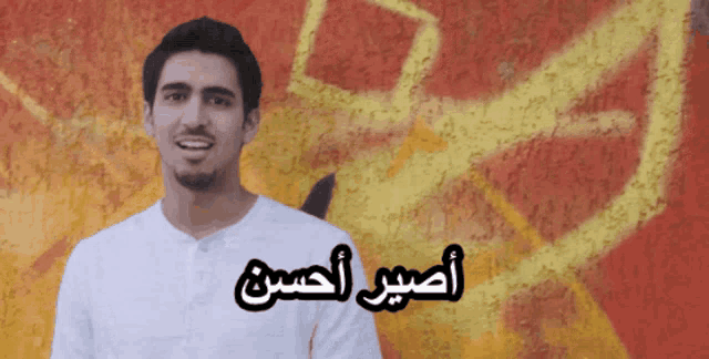 a man stands in front of a wall with the name amir written on it