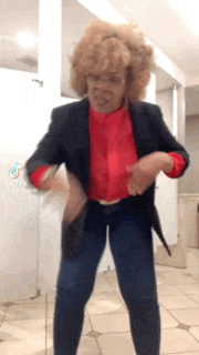 a woman with curly hair and glasses is dancing in a bathroom .