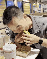 a man is sitting at a table eating a burger