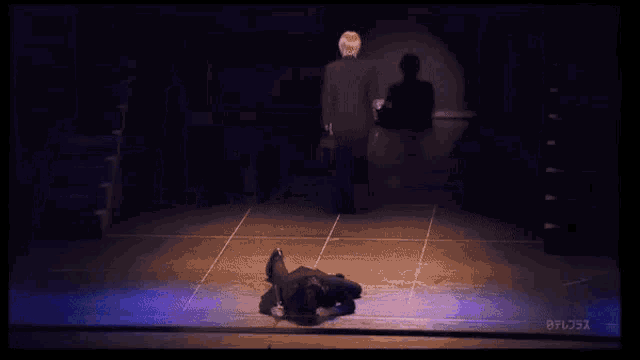 two men are standing next to each other on a stage and one is holding a sword .