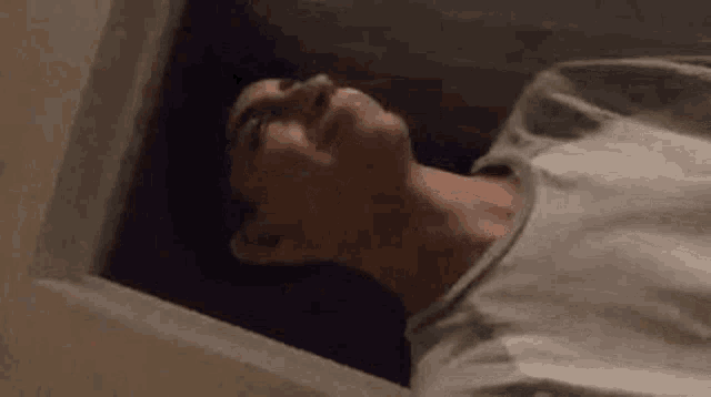 a young man is laying on his back in a dark room looking up .