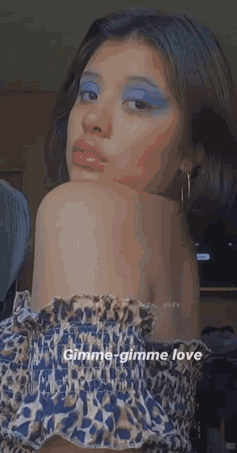 a woman wearing blue eyeshadow and red lipstick is taking a selfie .