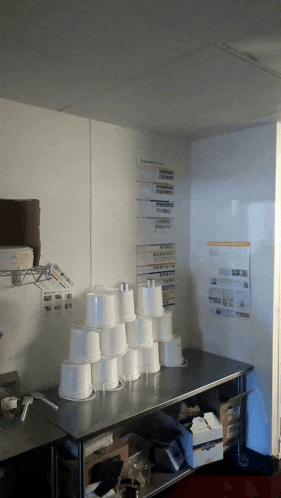 a stack of styrofoam cups sits on a table in a kitchen