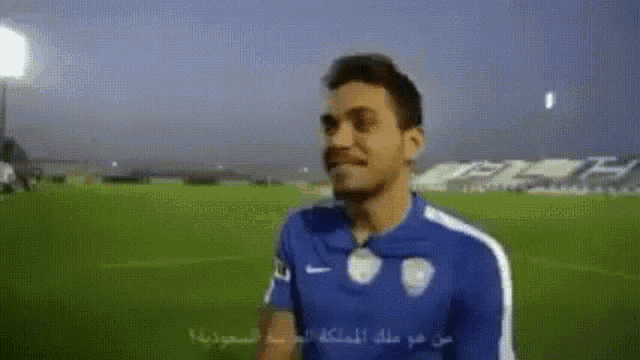 a man in a blue nike shirt stands on a field