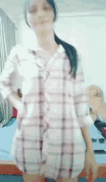 a woman in a plaid shirt is standing in a bedroom
