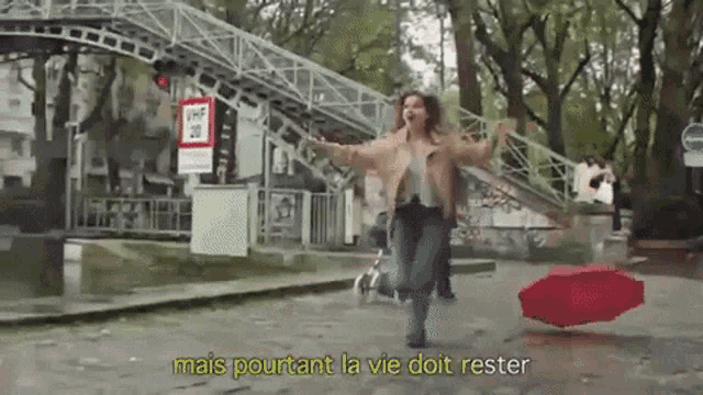 a woman holding a red umbrella in the rain with the words mais pourtant la vie doit rester