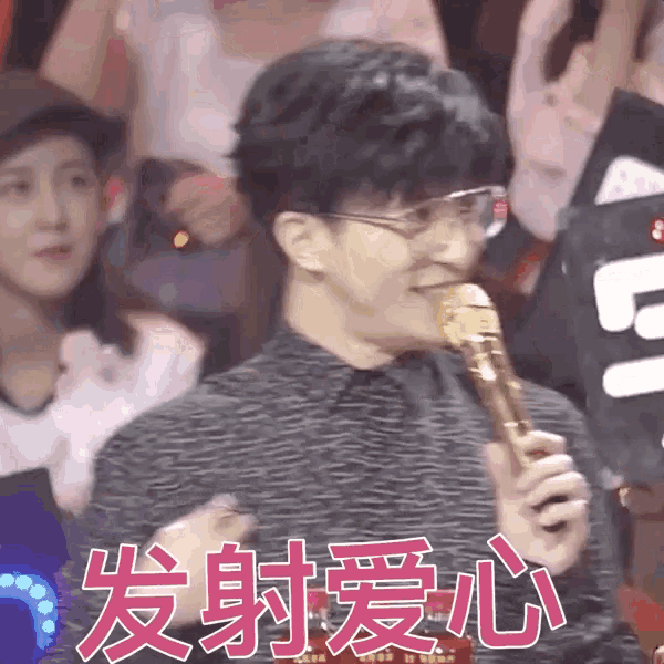 a man wearing glasses is holding a microphone in front of a crowd in chinese writing